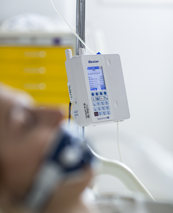 A patient in a hospital bed with a ventilator. Spectrum IQ is on a pole in the background.