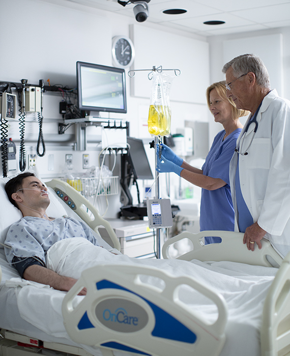 A doctor and a nurse checking in on a patient in a hospital room.