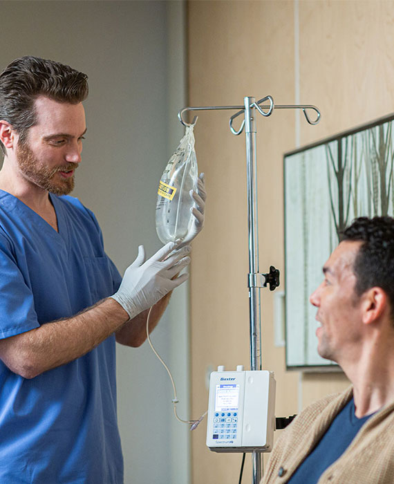 A nurse checking an infusion and a patient in a hospital room.