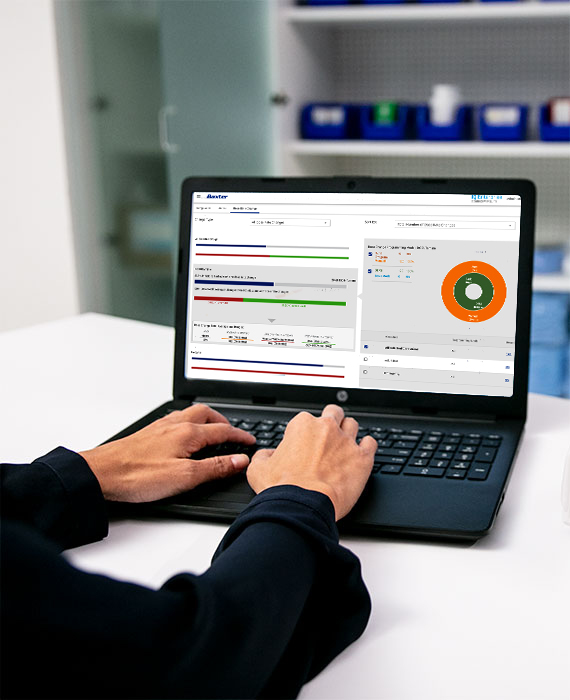 Pharmacist sitting at a desk reviewing data on a laptop. 