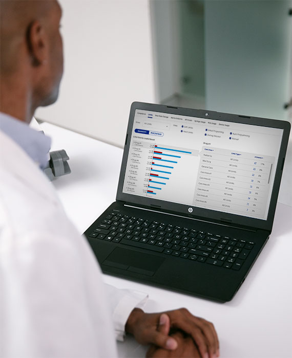 Pharmacist sitting at a desk reviewing data on a laptop. 